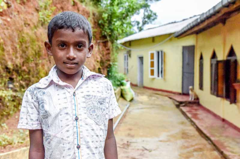 A boy standing outside his home