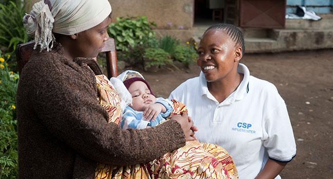 A mother holding her infant child during a home visit