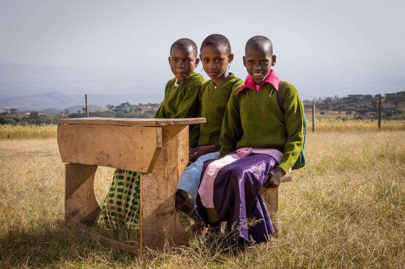 Three students sit at a desk outside