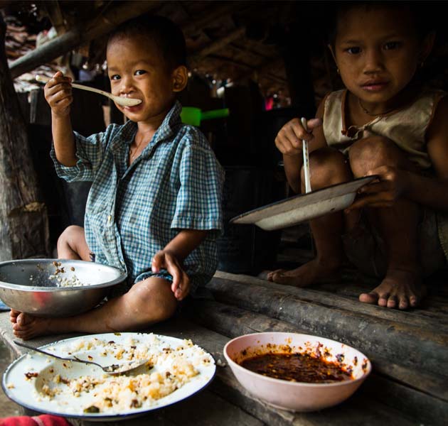 Young children sitting in their home eating a meal