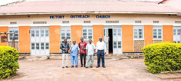 A group of people standing in front of a church in Uganda