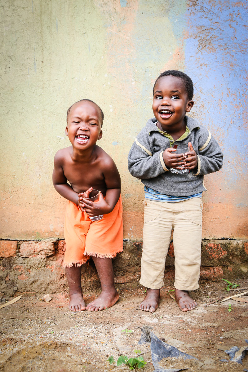 Two young boys stand against a wall as they play and laugh