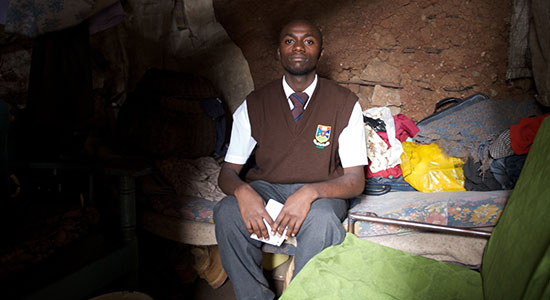 A Kenyan teenager sits on his couch/bed in his home in the Mathare Valley slum of Nairobi