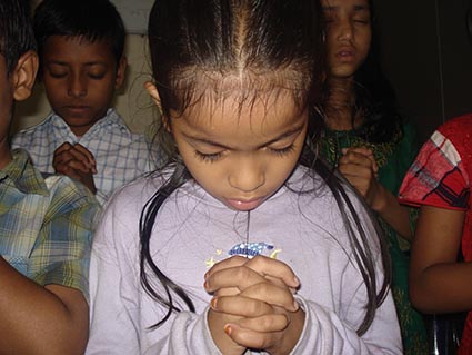 a girl bows her head in prayer