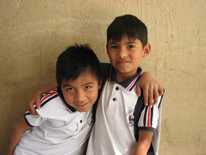 two boys standing together with their arms on each other's shoulders