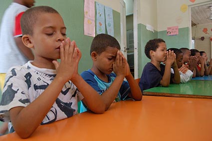 several children at a table are praying