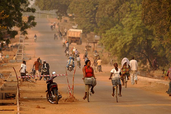 A road in Burkina Faso with many people riding bikes