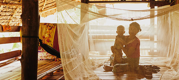 A mother and baby underneath a malaria mosquito bed net