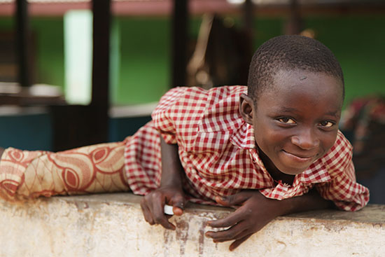 A boy in Ghana climbing over a wall