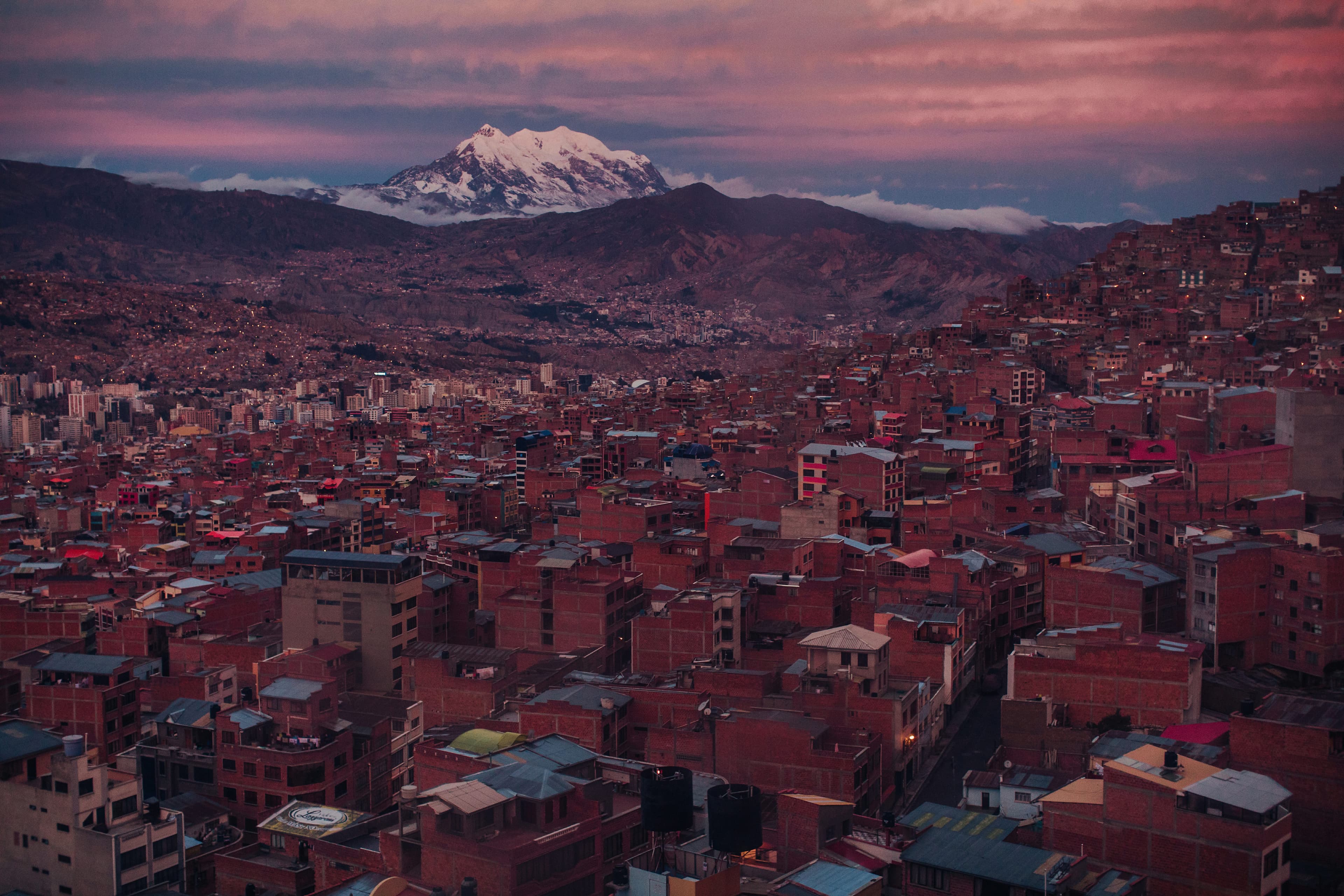 Image shows a landscape of buildings in front of a snowcapped mountain in Bolivia.