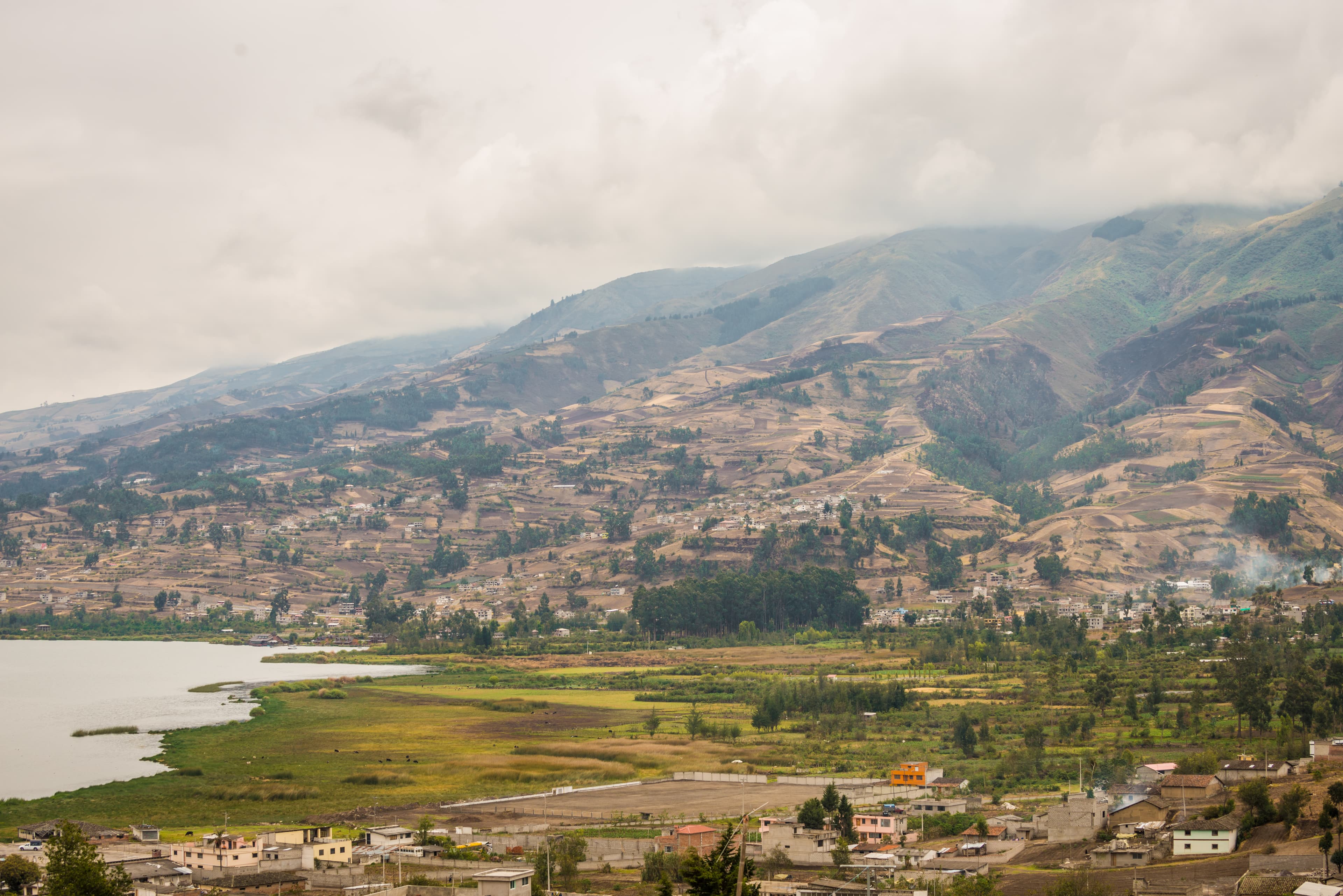 A landscape of lush green grass and water in front of rolling hills.