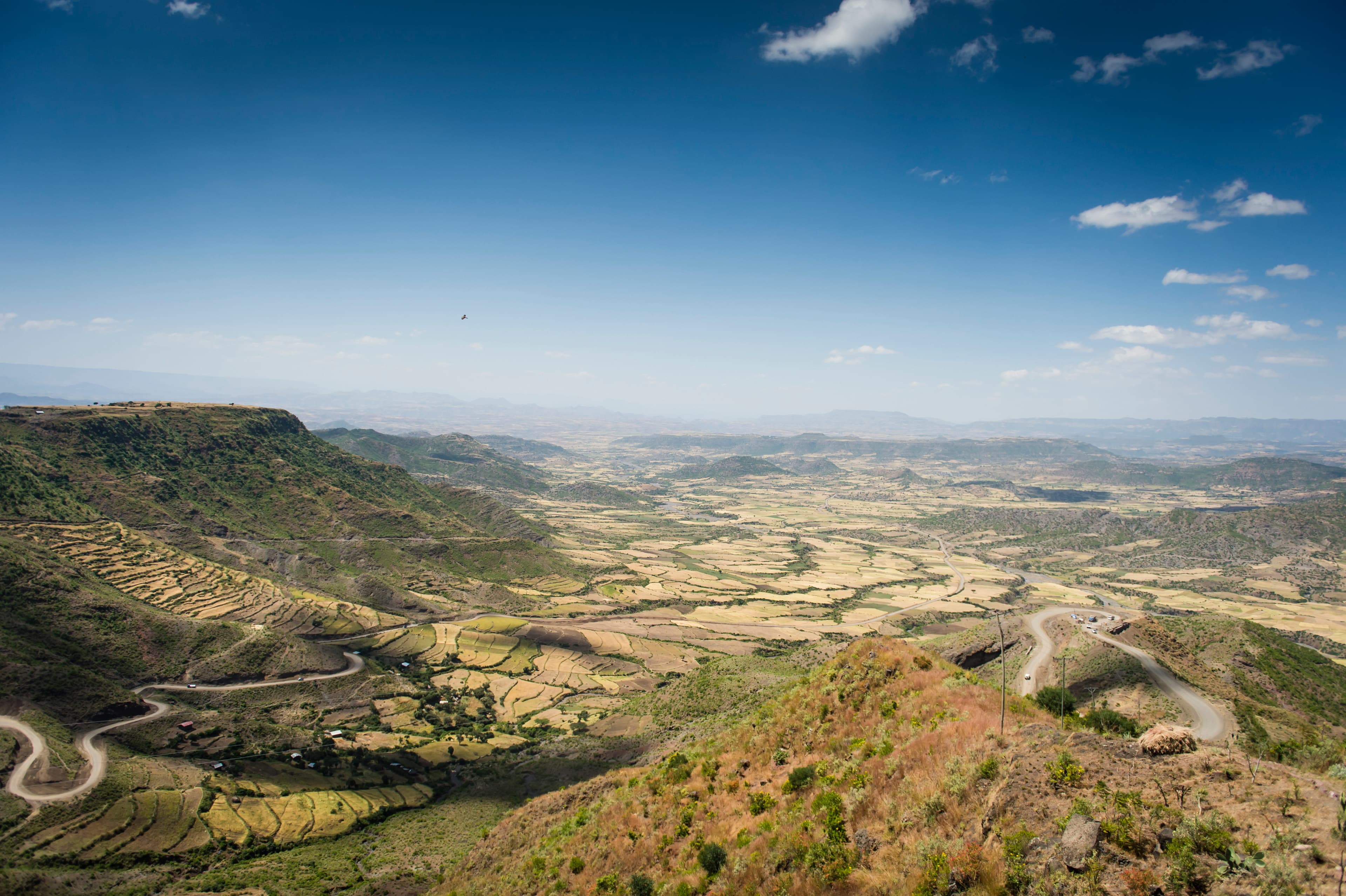 Fields and lush green landscape spread in front of a bright blue sky.