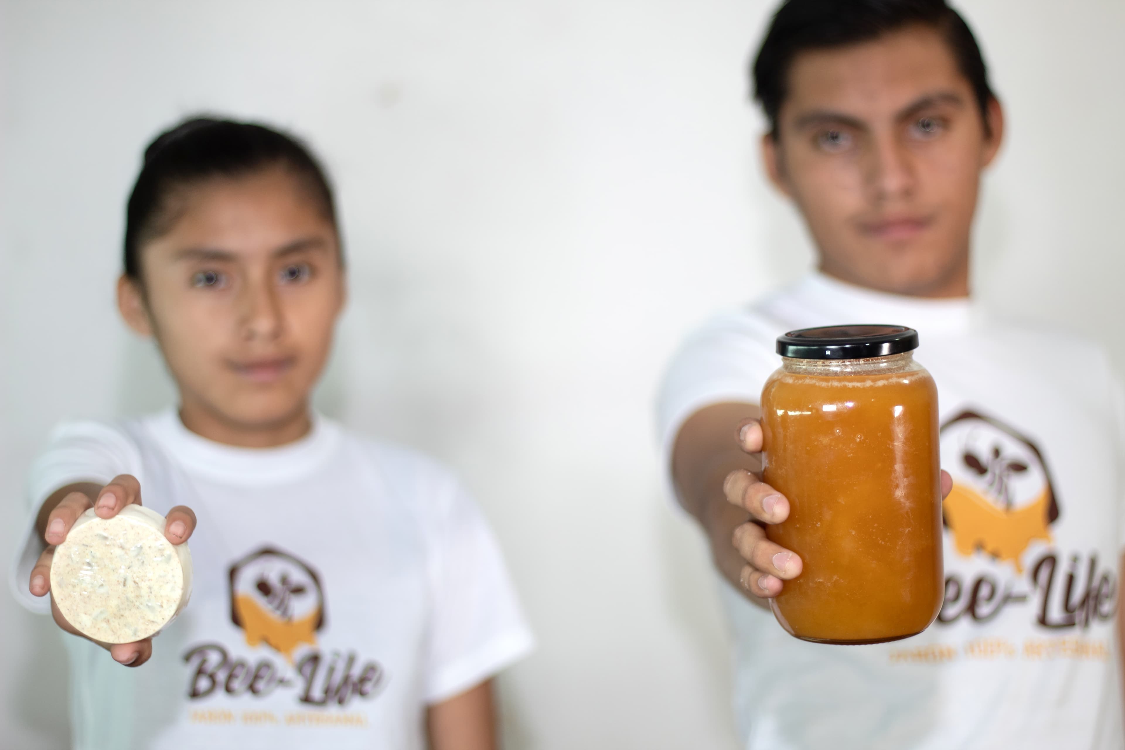 A young man and a young girl hold honey products they created through a program in Mexico.