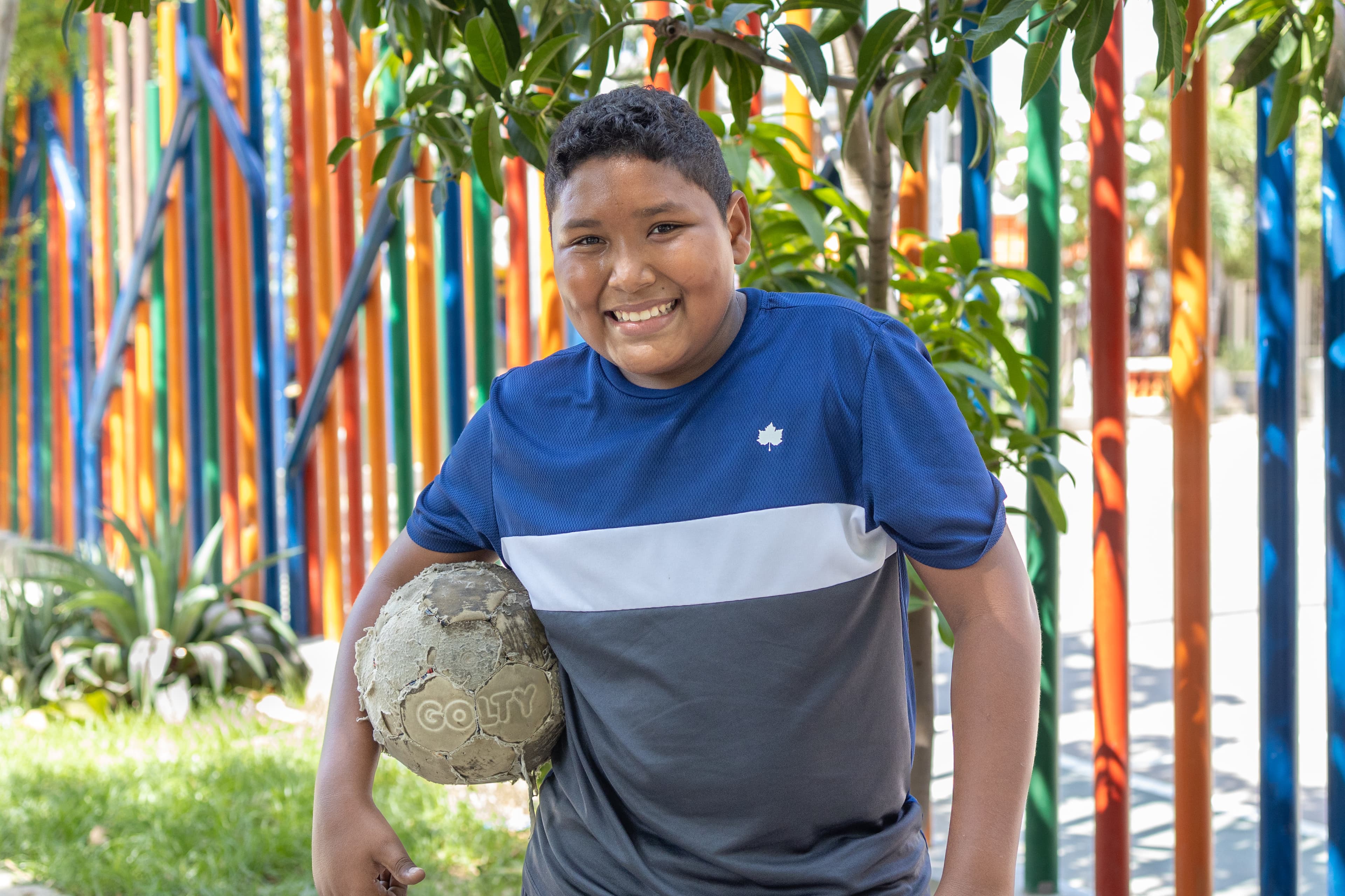 A young boy smiles while holding a soccer ball.