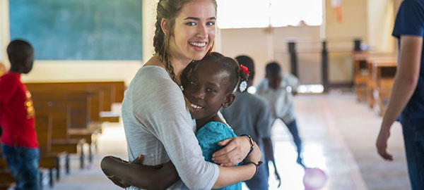 A young woman hugs a Compassion center child
