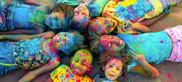 Kids lay in a circle laughing, covered in paint