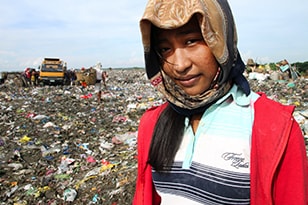 Girl with a head covering in a garbage dump