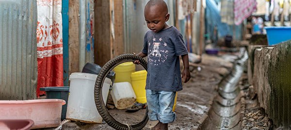 A boy playing with an old tire in the street