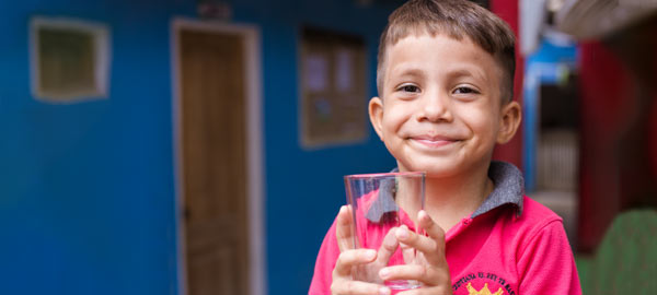 A boy holding a glass of clean safe water