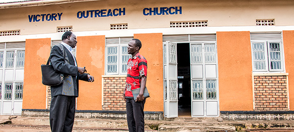 two men speaking to one another in front of a church
