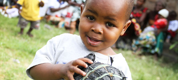 A young boy smiles while holding a ball