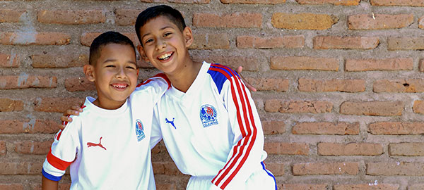 Two boys smile in soccer uniforms