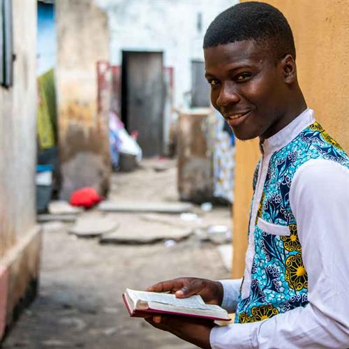 a teen looks at the camera while holding a bible