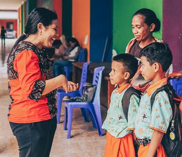 A woman speaks to a group of children