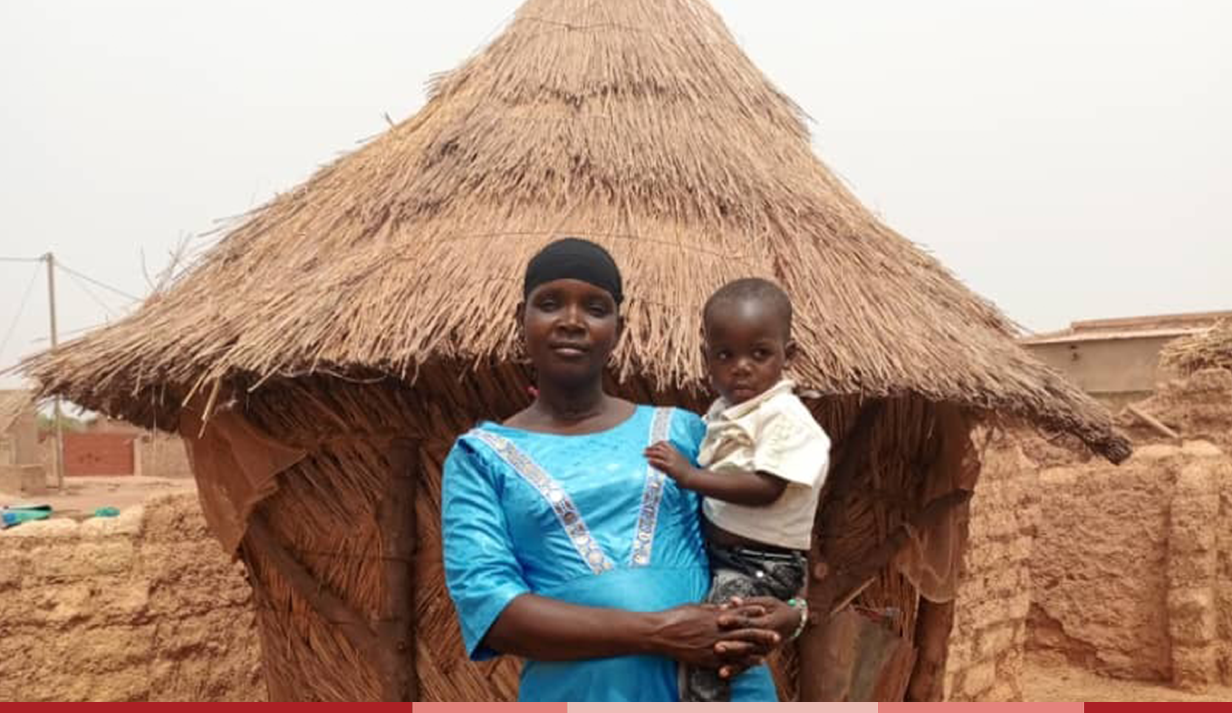 Maria smiles while holding baby Amza outside their home