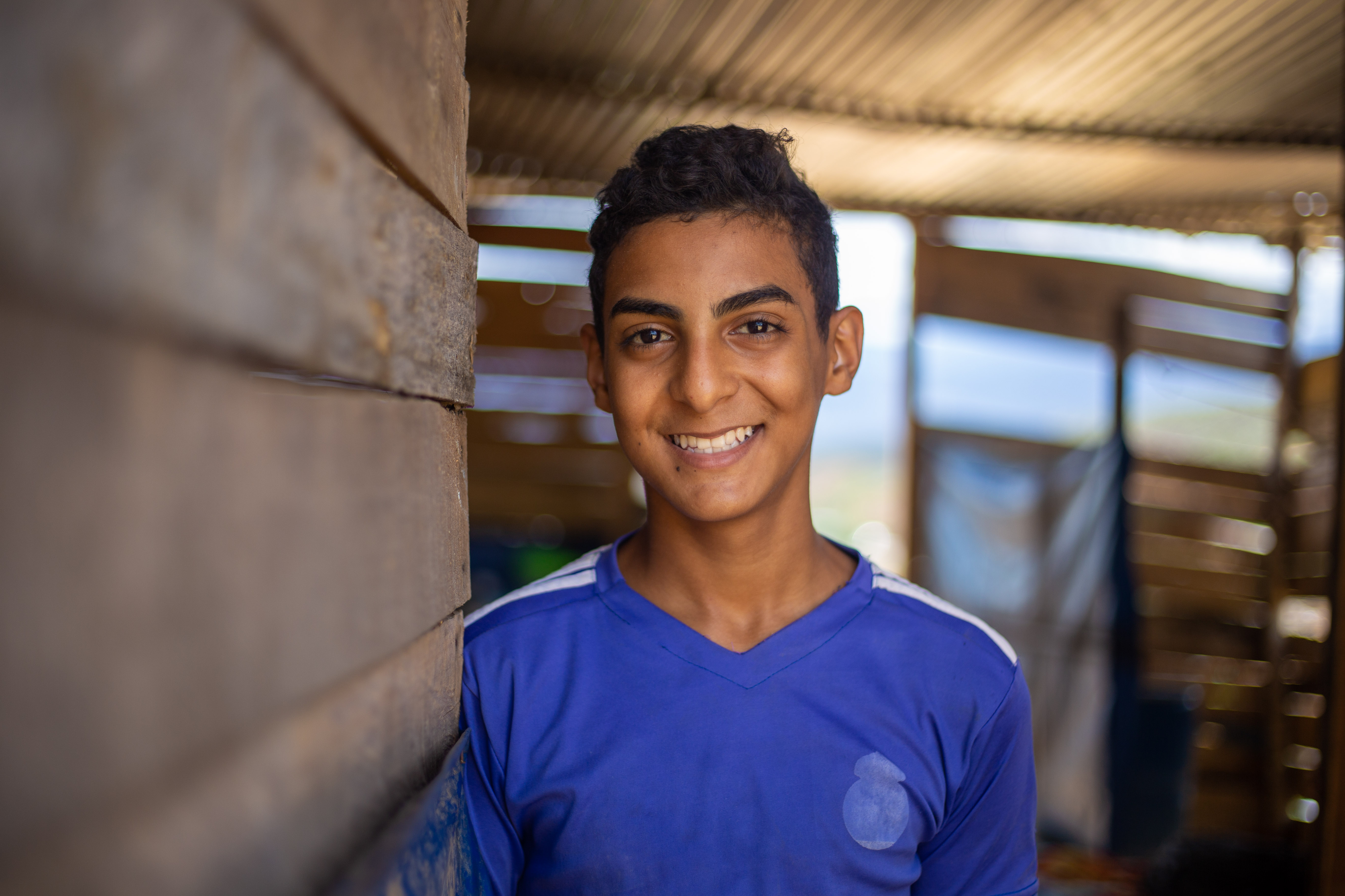 Jesús, a teenage boy smiles at the camera wearing a blue shirt
