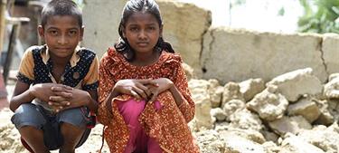 two children sit on rubble