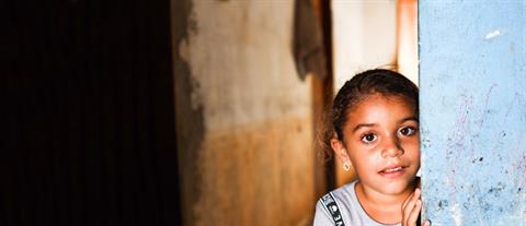 A girl stands inside next to a wall