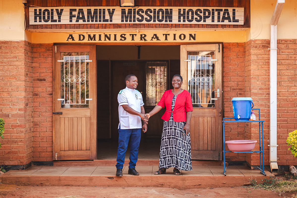 Pastor Beauty shaking hands with hospital staff in front of the hospital.