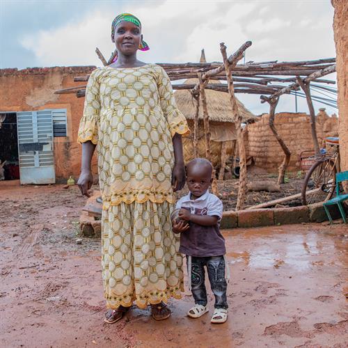 Maria stands outside beside her son Amza