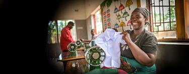 a woman smiles brightly as she proudly displays a white t-shirt she tailored