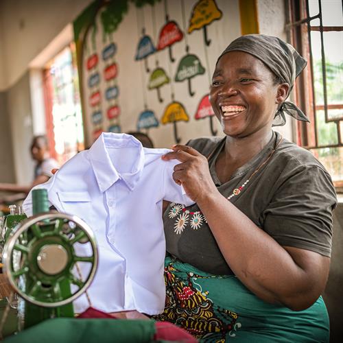A mom smiles brightly as she shows a t-shirt she tailored