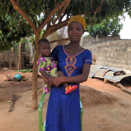Agbessinou holds her baby while standing outside 