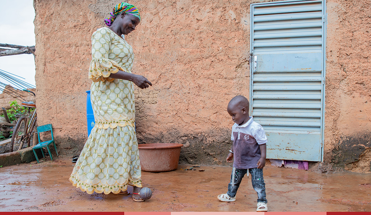 Maria stands next to her toddler who plays outside