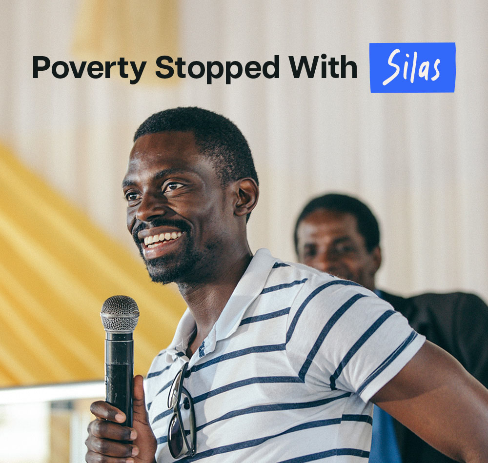 Silas holds mic and smiles at camera