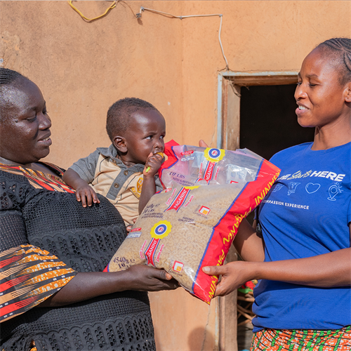A smiling woman and her baby receiving a bag of pasta 