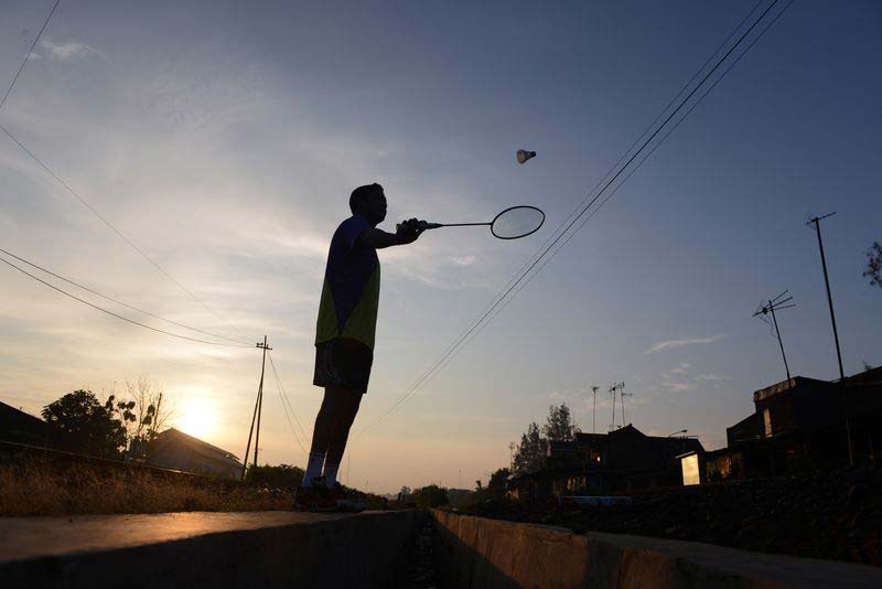 Fredy practices swinging his badminton racket