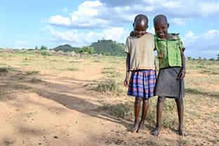 2 boys stand with their arms around each other