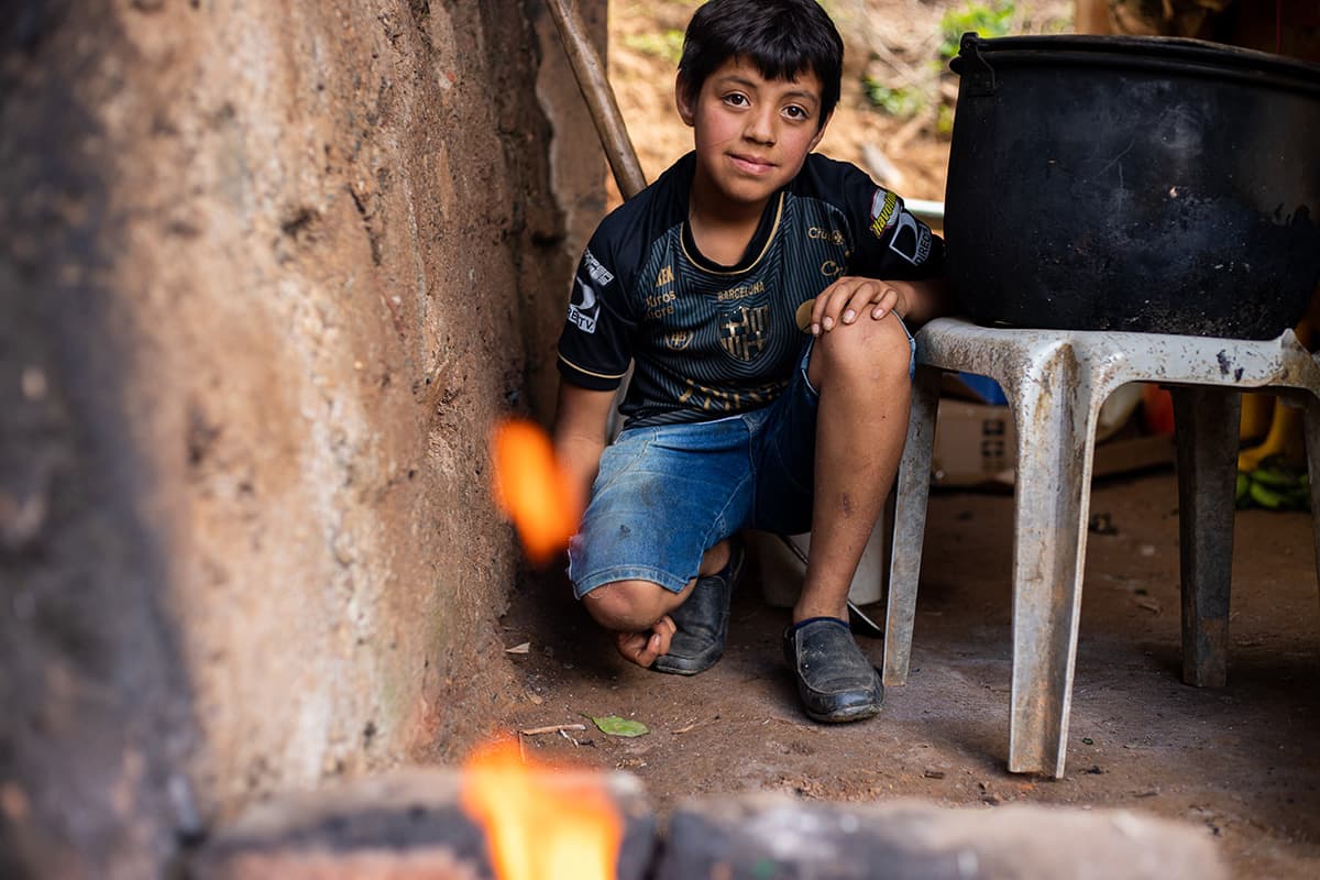 Boy kneeling beside a chare in front of a fire