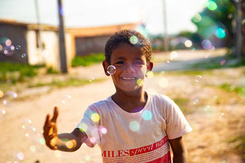 A boy smiles while playing with bubbles