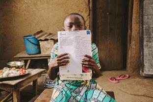 A child holds up a letter from a sponsor
