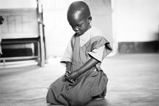 A child kneels and prays