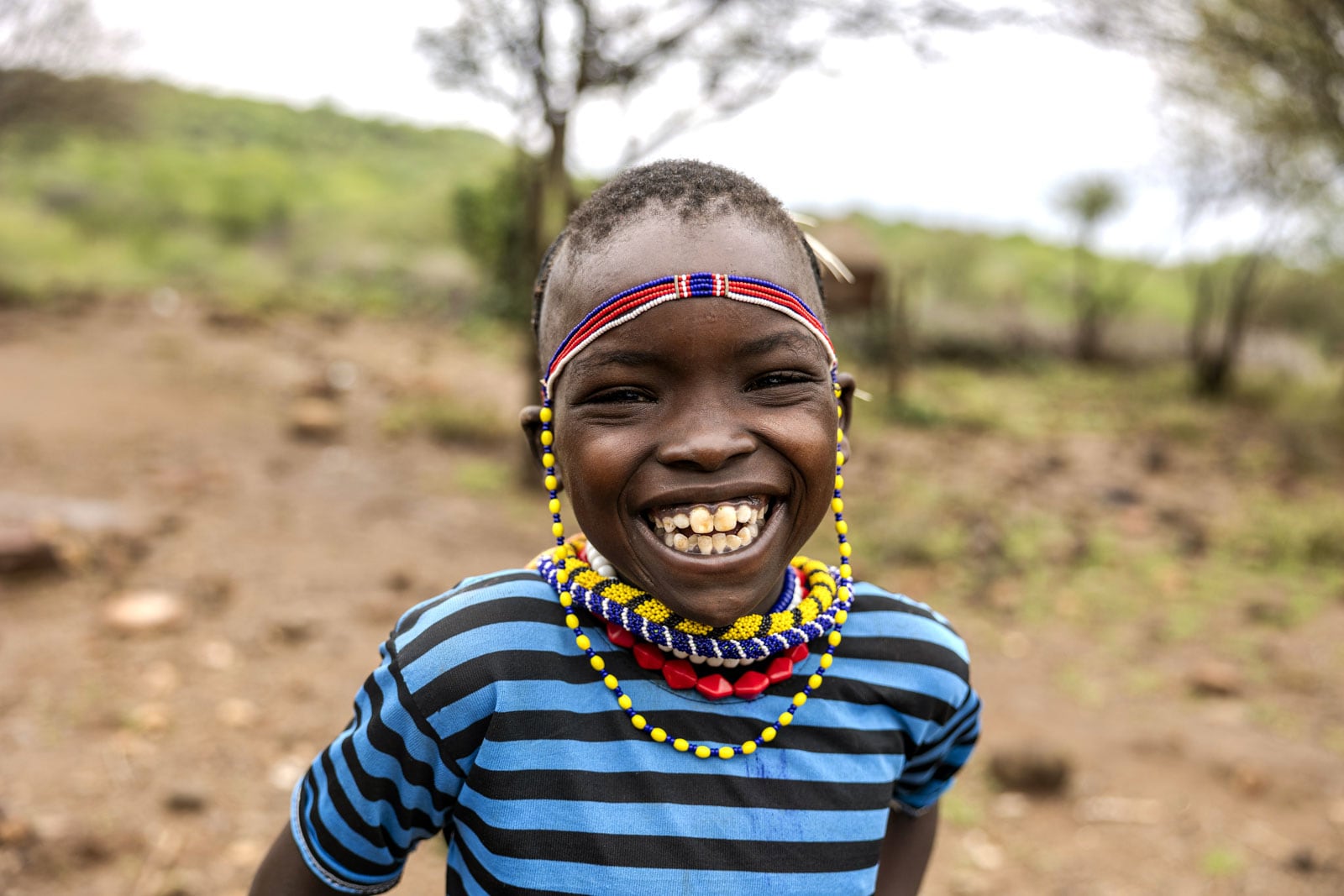 Child smiling wearing Kenyan bead necklaces