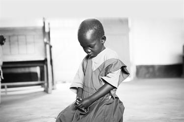A young child kneels and prays