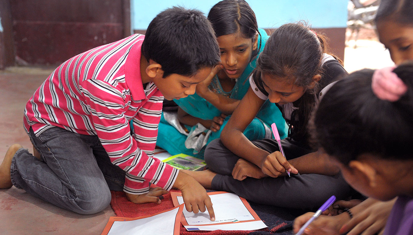 A group of children helping each other with schoolwork