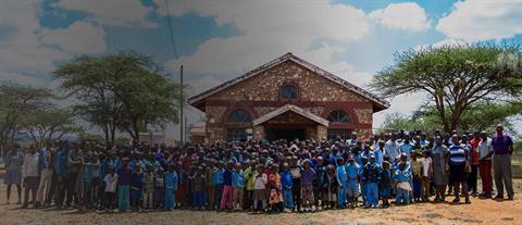 A group of adults and children standing in front of a church in Kenya